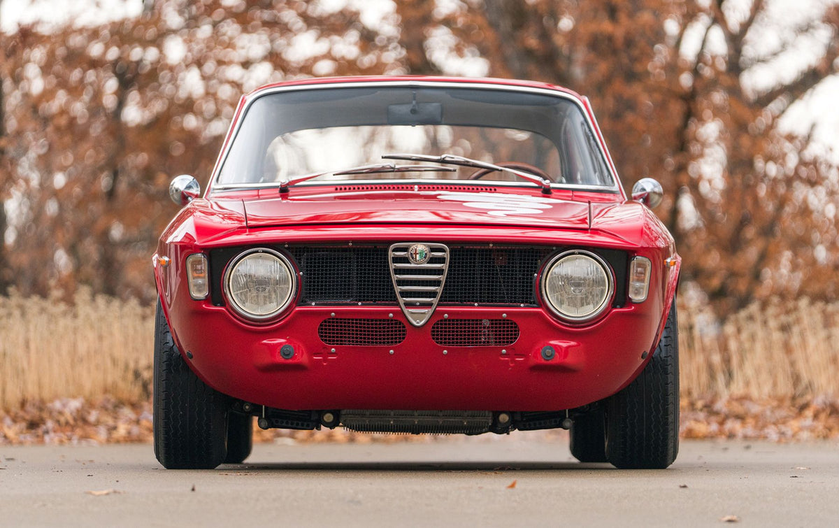 Red vintage Alfa Romeo Giulia race car, head-on, with mesh in the grille and lower intakes