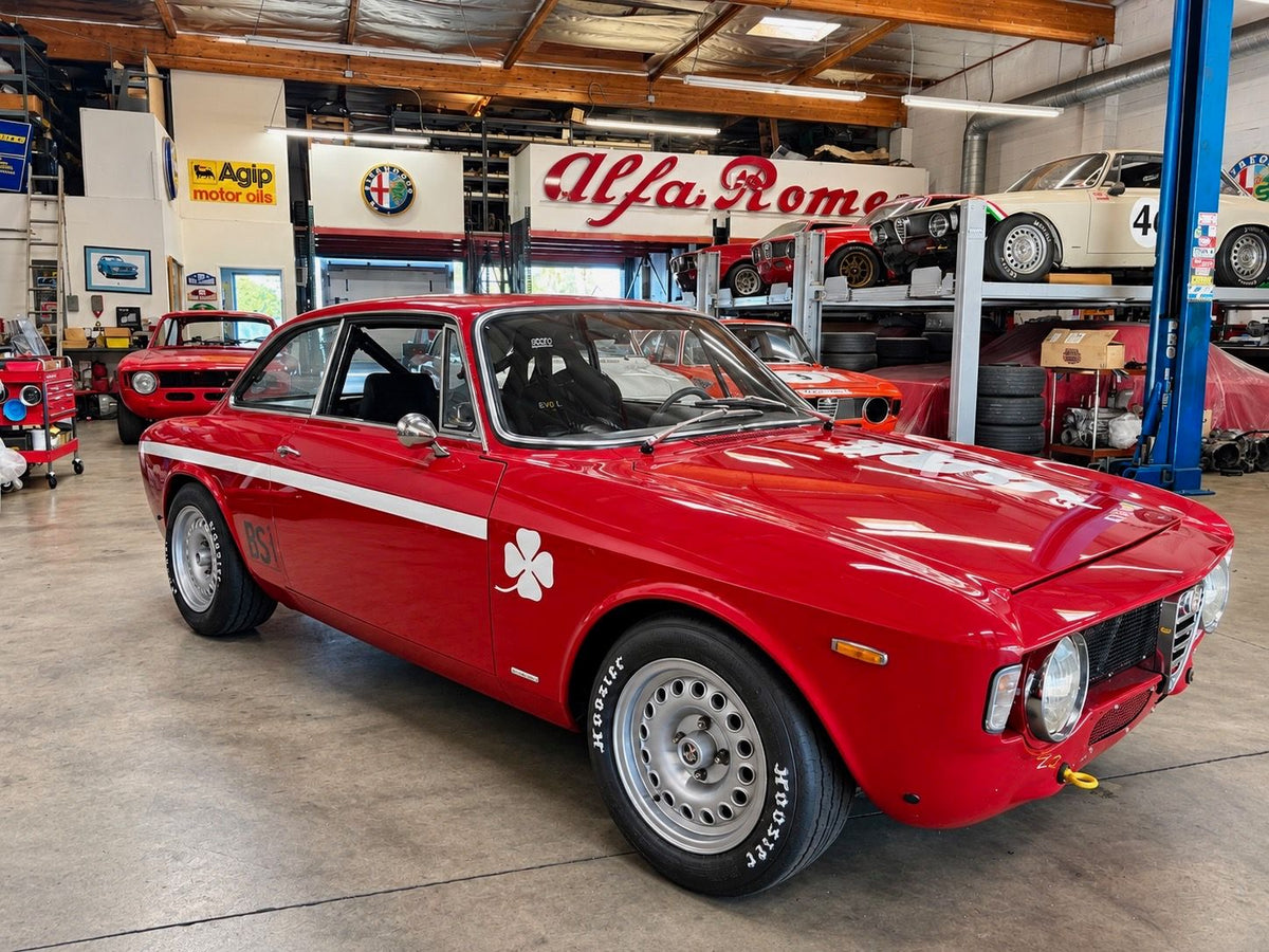Red vintage Alfa Romeo Giulia race car parked in an Alfa Romeo shop