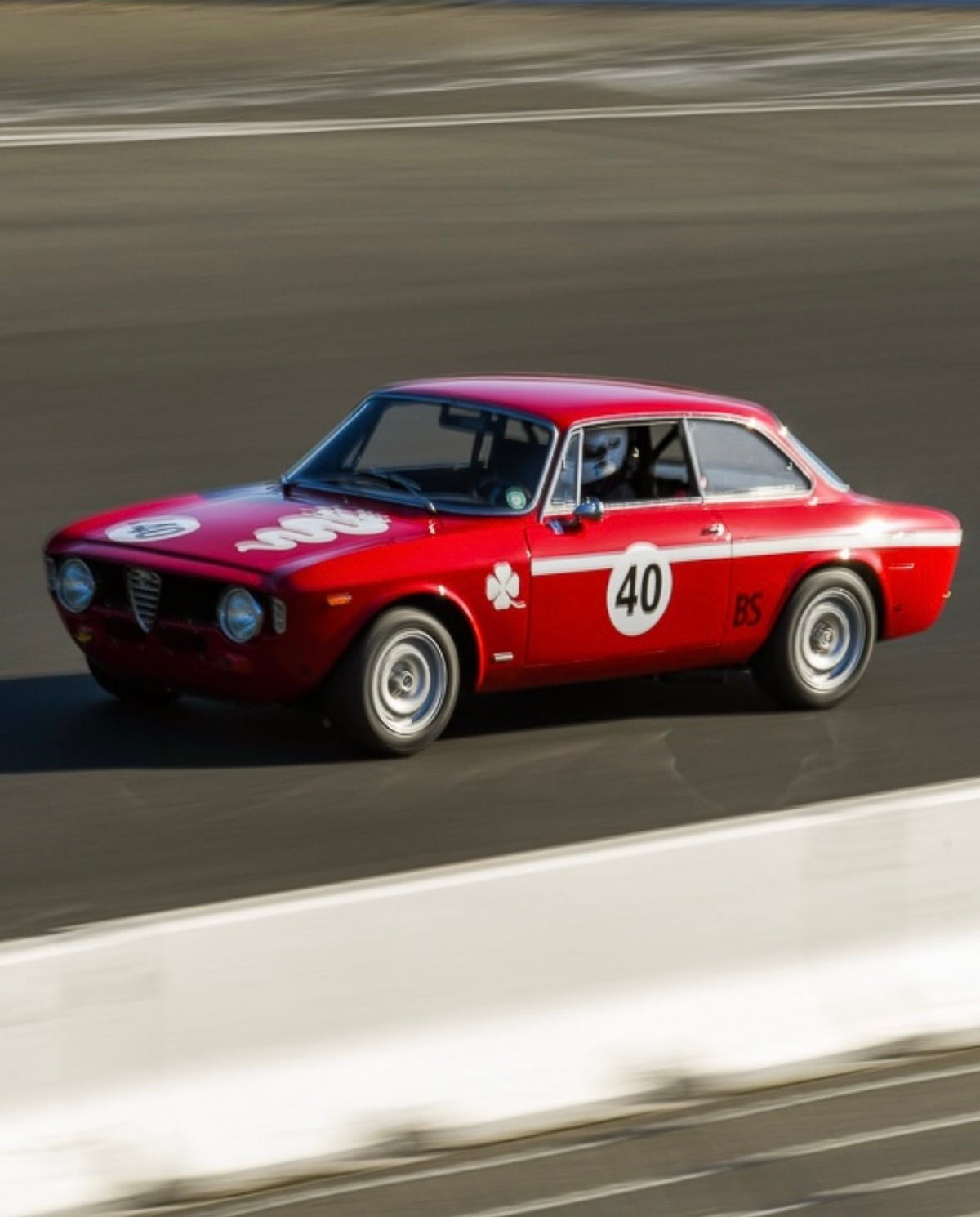 Red vintage Alfa Romeo Giulia, race number 40, at speed on a track