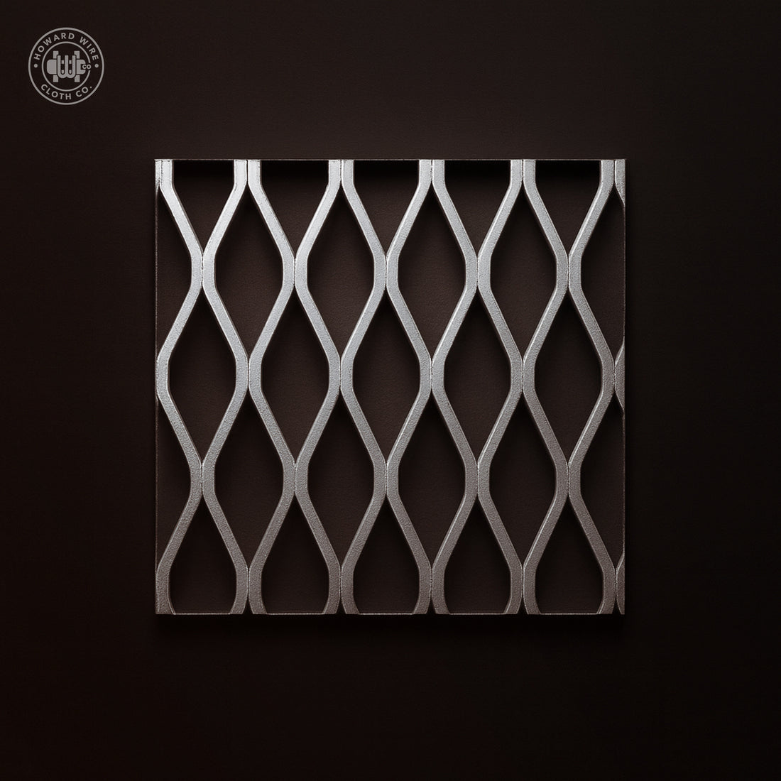 Studio product photograph of aluminium flattened expanded metal, 1-1/2 inch .125, showing diamond openings, on a dark graphite background.